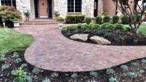 A well-maintained lawn and newly planted garden beds with fresh mulch along a brick pathway by Mitera Landscaping in Papillion, NE.