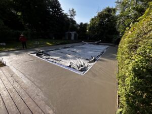 A newly poured concrete pool deck surrounding a covered swimming pool by Morton and Sons in Layton, UT