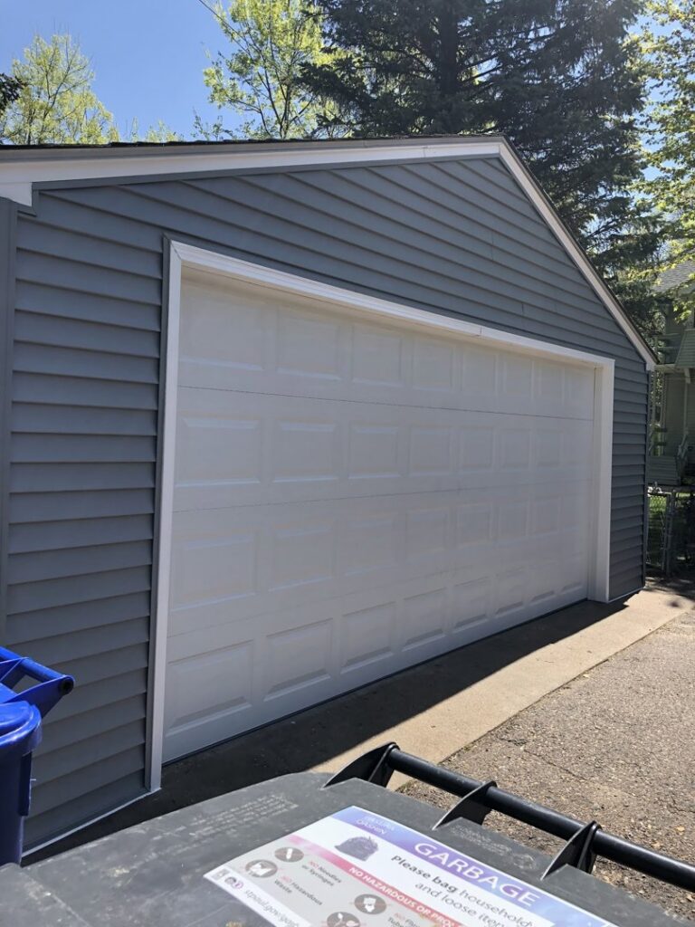 Newly sided garage with modern gray siding and a white garage door by Capital Siding, Windows & Roofing, Woodbury, MN.