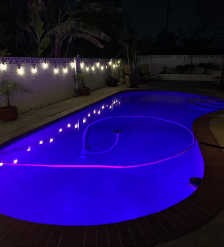 A pool cleaner hose working in a beautifully lit pool at night, providing service by Overflow Poolz LLC in Las Vegas, NV.