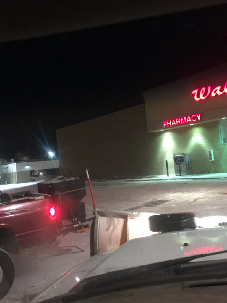 Night snow plowing at a Walgreens parking lot by TLC Lawn Care and Snow Removal LLC in Colorado Springs, CO.