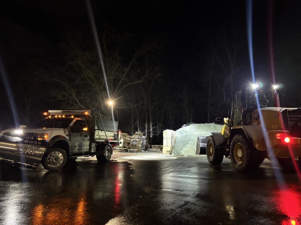 A snow plow truck and front-end loader working at night, preparing for or performing snow removal services for C&S Lawncare in Ann Arbor, MI.