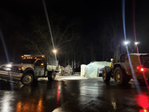 A snow plow truck and front-end loader working at night, preparing for or performing snow removal services for C&S Lawncare in Ann Arbor, MI.