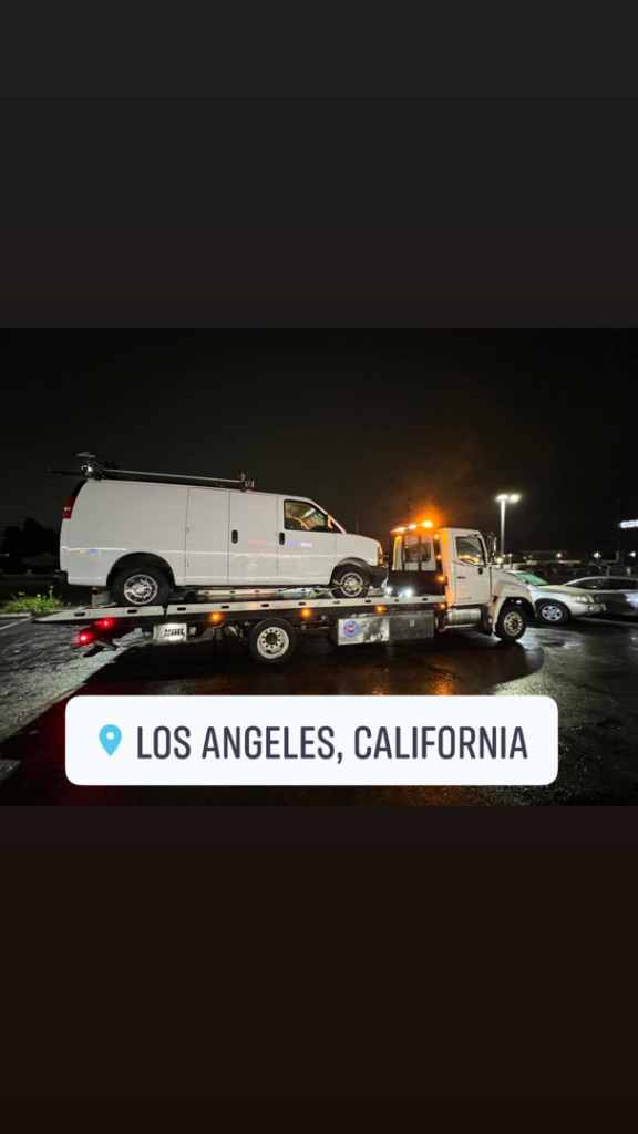 Sotelo Towing LLC providing night towing service for a white van on a flatbed tow truck in Phoenix, AZ.