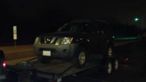 A Nissan Xterra being towed on a trailer at night by Jr & Sr towing and recovery in Waukegan, IL.
