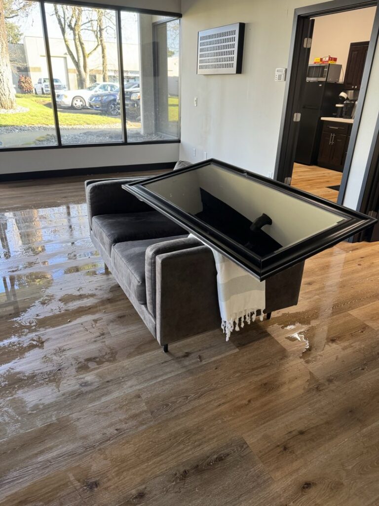 An office space with water damage on the floor and a wet couch, ready for restoration by Verg Restoration in Vancouver, WA