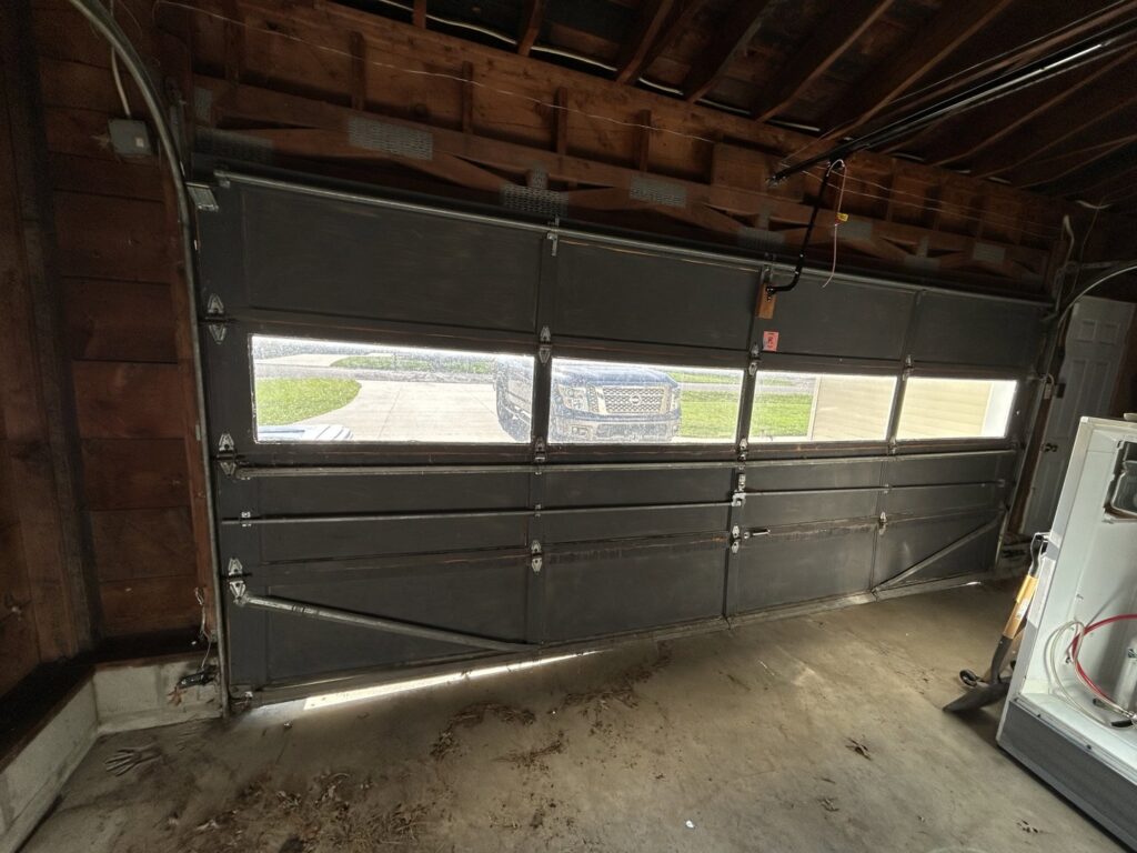 Interior view of an old, damaged garage door before replacement by Cedar Valley Garage Doors in Waterloo, IA