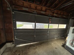 Interior view of an old, damaged garage door before replacement by Cedar Valley Garage Doors in Waterloo, IA