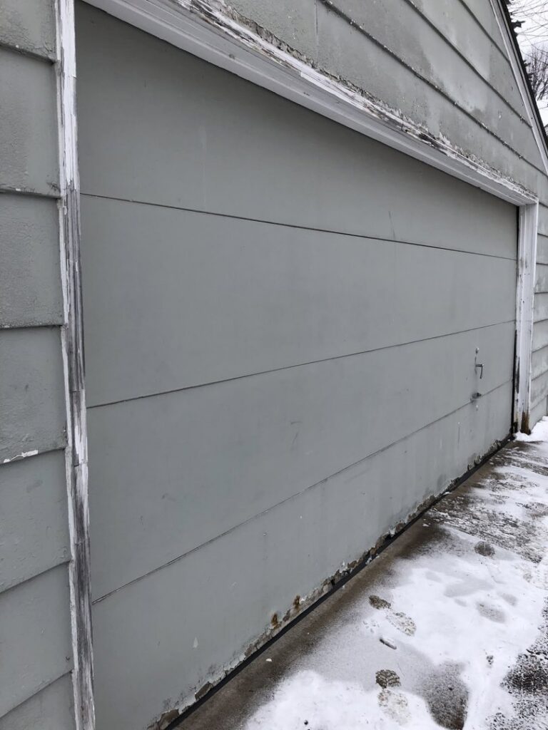 Old garage with damaged and peeling siding, showing need for repair by Capital Siding, Windows & Roofing, Woodbury, MN.