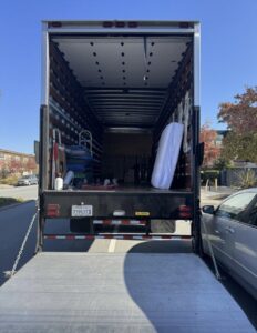 The open back of an IMoving Professional Moving System Inc. moving truck with a ramp, showing moving blankets and a mattress inside in San Francisco, CA