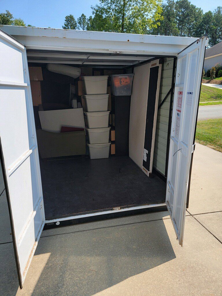 An open storage unit partially filled with household items, managed by Rambling Man Logistics in Hildebran, NC.
