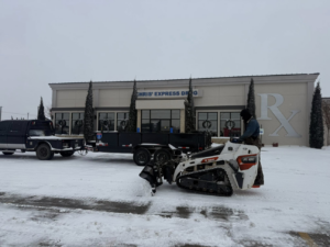 An operator clearing snow from a commercial parking lot with a skid-steer loader for Trusted Fencing LLC in Moore, OK.