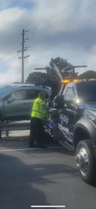 A Bobbys Towing & Recovery operator securing a silver SUV onto a flatbed tow truck in Raleigh, NC.