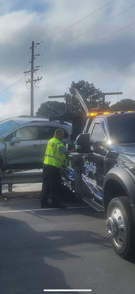 A Bobbys Towing & Recovery operator securing a silver SUV onto a flatbed tow truck in Raleigh, NC.
