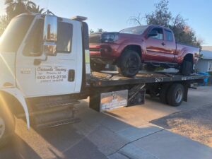 An orange forklift being transported on a flatbed tow truck by Crisanto Towing in Phoenix, AZ.