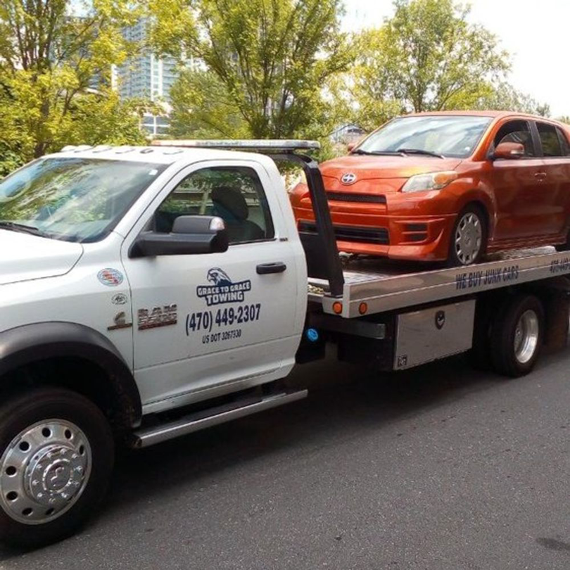 An orange Scion xB being transported on a flatbed tow truck by Grace to Grace Towing in Atlanta, GA.