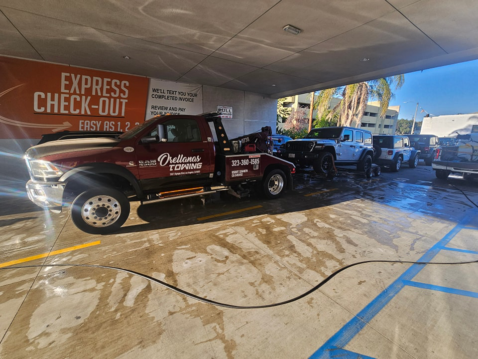 An Orellanas Towing truck actively towing a white Jeep Wrangler in Los Angeles, CA.