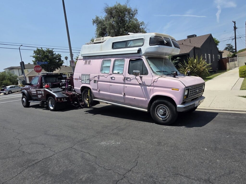 An Orellanas Towing truck actively towing a pink camper van in Los Angeles, CA.