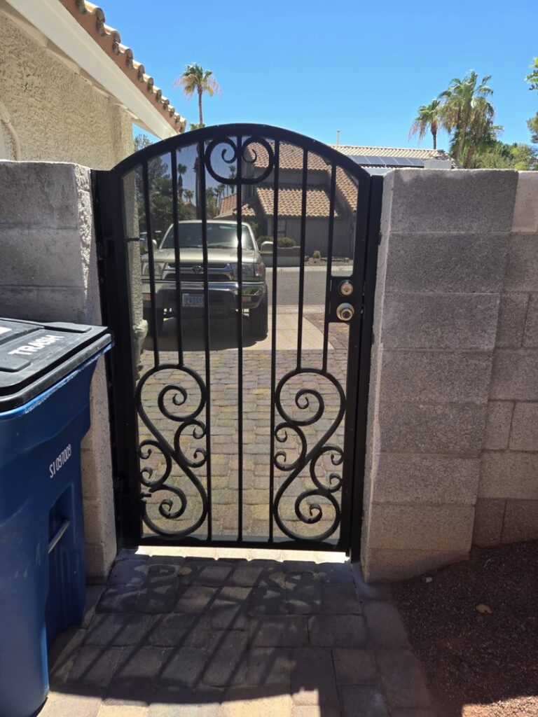 An ornate black iron pedestrian gate installed by Giddy Up Garage Doors & Iron in Las Vegas, NV.
