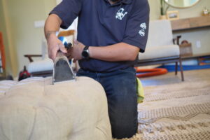 A house cleaner from Idaho Gem Cleaning performing professional upholstery cleaning on an ottoman in Caldwell, ID.