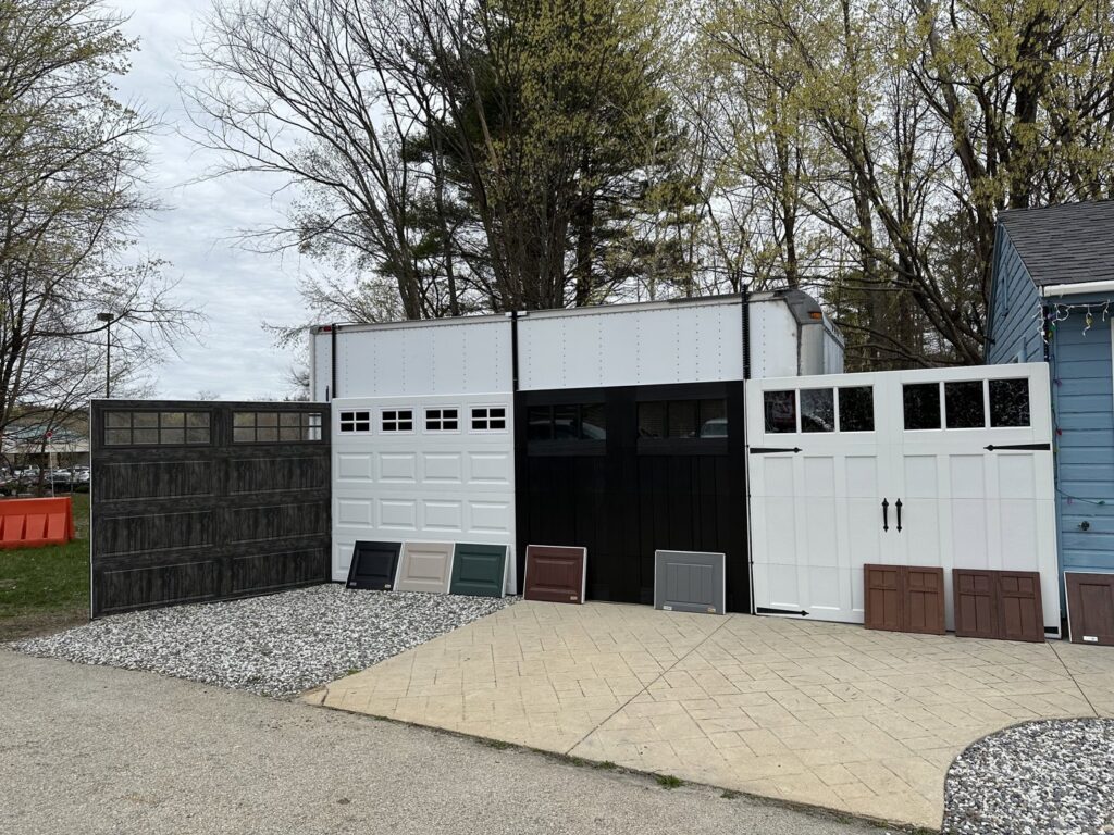 An outdoor display showcasing various styles and colors of garage doors, available from Steve Shumsky Unlimited Overhead Doors LLC in Hudson, NH
