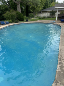 An oval-shaped, clean blue in-ground pool, reflecting the quality service of Pips Pool Service in Enid, OK.