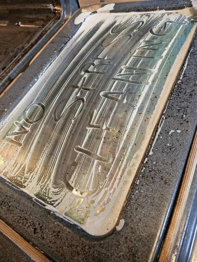 An oven door being cleaned with foam, showing "No Stress Cleaning" written, by No Stress Cleaning Services in Virginia Beach, VA