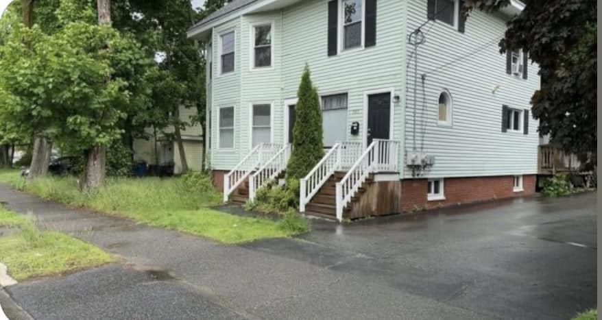 An overgrown lawn and garden bed before professional care by Steele Lawns in Portland, ME.