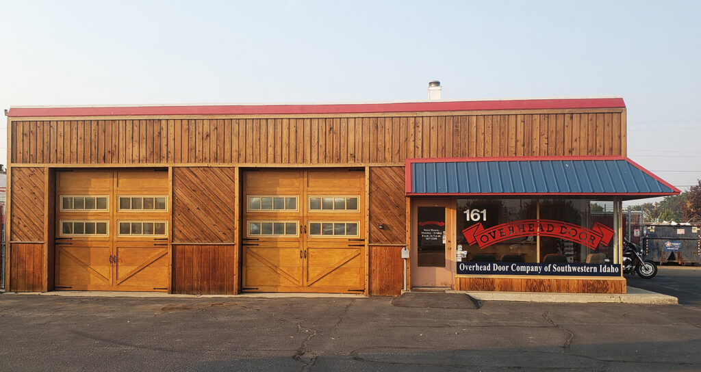 The exterior of Overhead Door Company of Nampa's building featuring three wooden garage doors in Nampa, ID.
