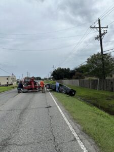 An overturned black car being recovered from a ditch by Rick's Towing and Recovery in Lafayette, LA.