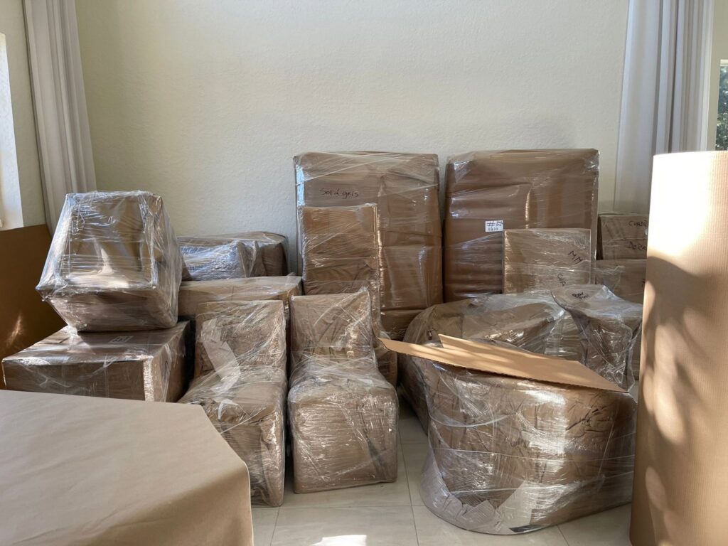 A room filled with neatly packed and wrapped furniture and boxes, prepared for moving by Orellana AV Moving in Miami, FL.