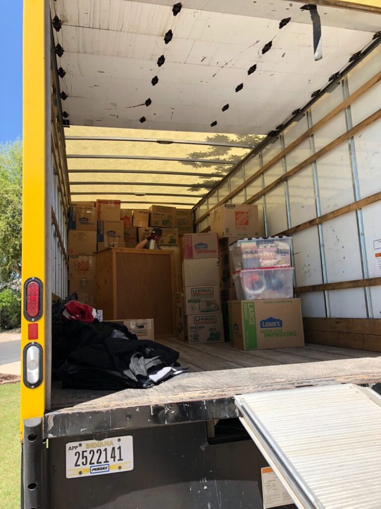 A moving truck fully loaded with boxes and household items, with the ramp extended, ready for transport by Academy Movers in Gilbert, AZ.