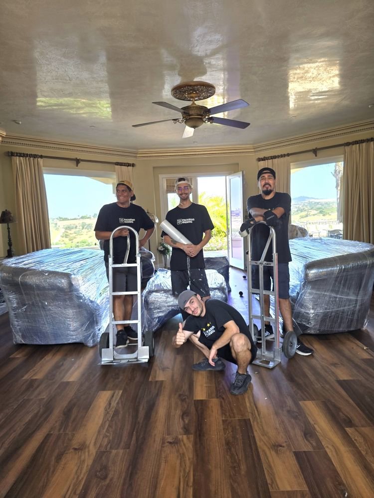 The Packman Moving team standing with wrapped furniture and dollies, ready for a move in San Diego, CA