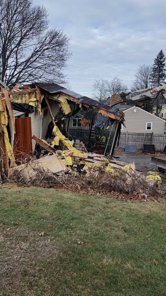 A partially demolished house with exposed insulation and debris, handled by Allied Wrecking Boston in East Boston, MA.