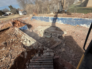 A partially demolished swimming pool, showing ongoing demolition work by Enfield Demolition & Excavation LLC in Enid, OK.
