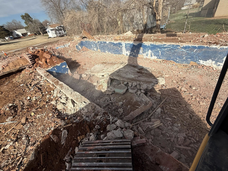 A partially demolished swimming pool, showing ongoing demolition work by Enfield Demolition & Excavation LLC in Enid, OK.