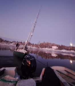 Downeast Marine Towing, LLC crew recovering a partially submerged sailboat in Eastport, ME during dusk.