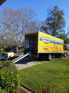 A yellow Penske moving truck with its ramp extended, ready for loading or unloading by Rough Çutt Movers in San Diego, CA.