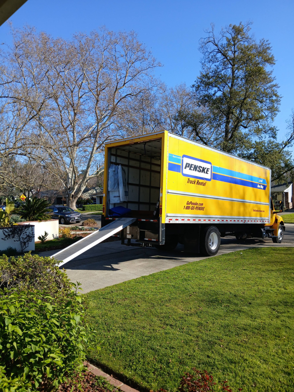 A yellow Penske moving truck with its ramp extended, ready for loading or unloading by Rough Çutt Movers in San Diego, CA.
