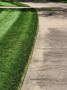 A close-up of a perfectly edged lawn next to a concrete path, showcasing meticulous detail by A & B Lawn Service LLC in Baytown, TX.
