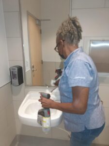 A professional cleaner sanitizing a bathroom sink and mirror, provided by Janice Janitorial LLC in Baton Rouge, LA.