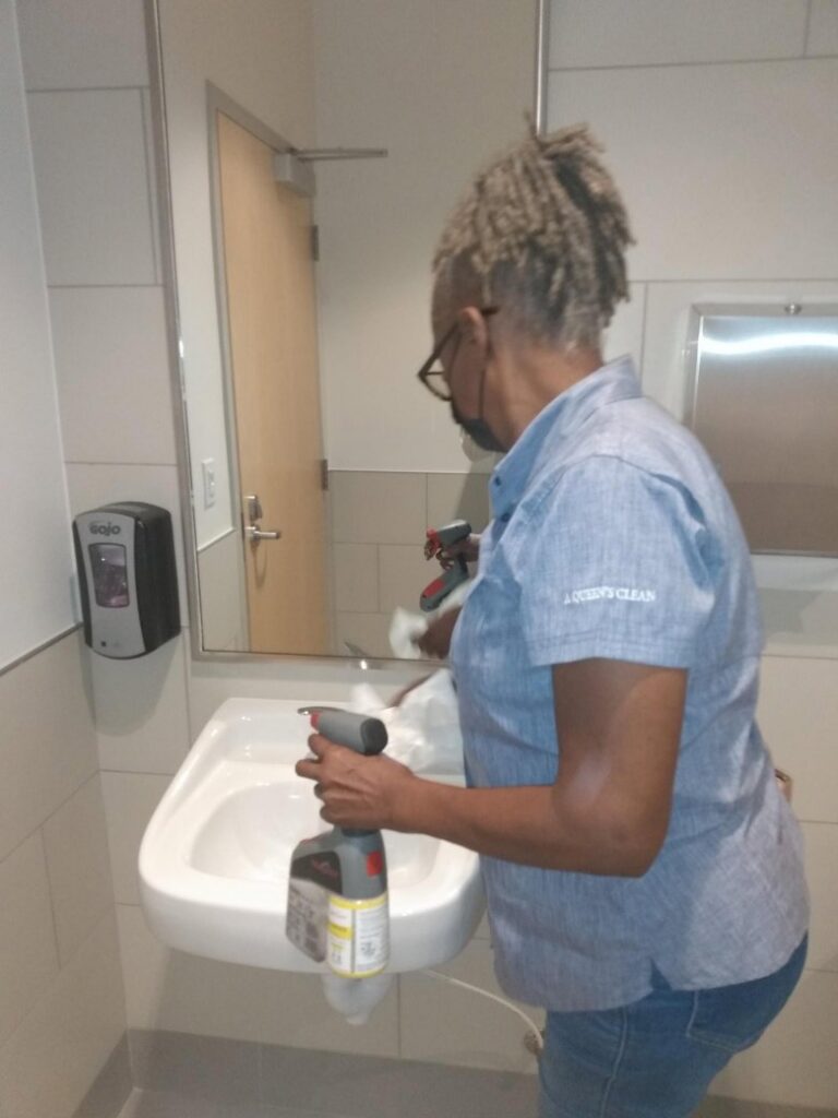 A professional cleaner sanitizing a bathroom sink and mirror, provided by Janice Janitorial LLC in Baton Rouge, LA.