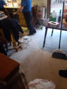 A person standing in a kitchen area with a broom, indicating house cleaning work by L & G Cleaning Service in Aurora, CO.
