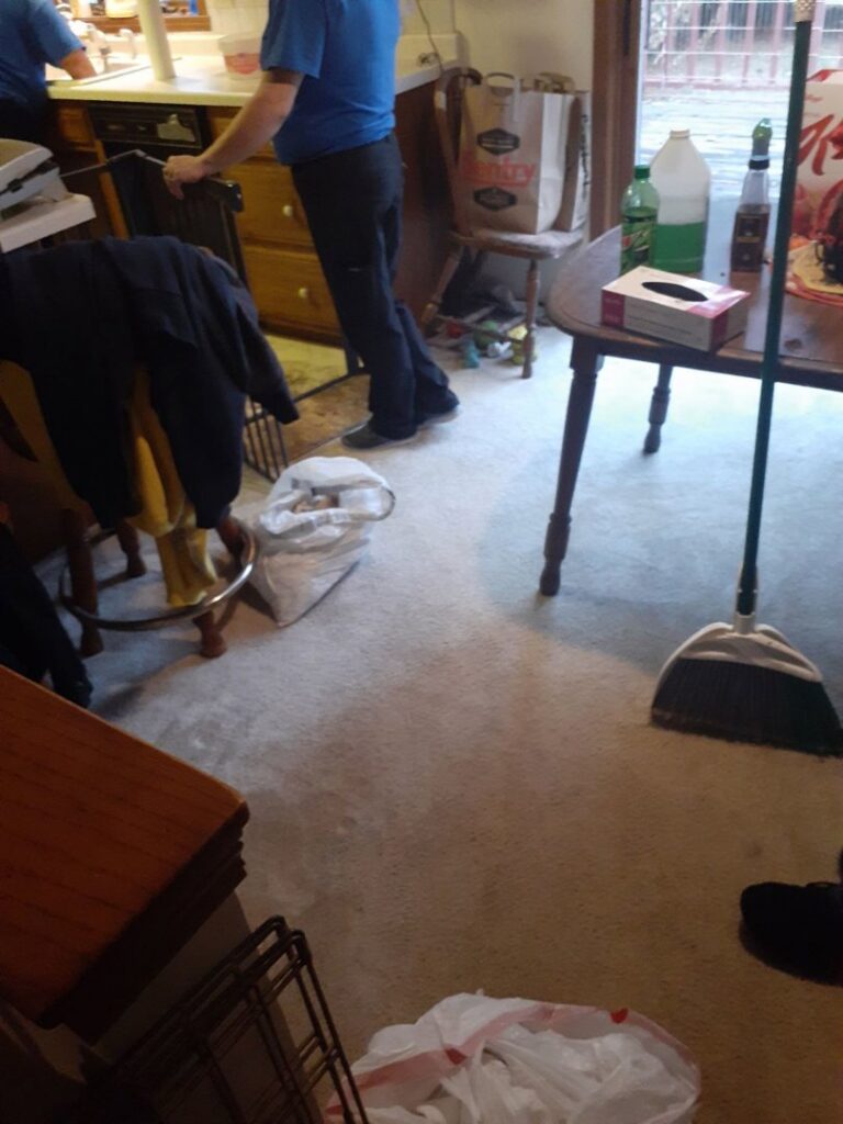 A person standing in a kitchen area with a broom, indicating house cleaning work by L & G Cleaning Service in Aurora, CO.