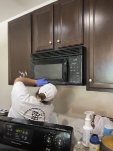 A Maximo Cleaning team member in Lexington, KY, meticulously cleaning a microwave and kitchen cabinets.