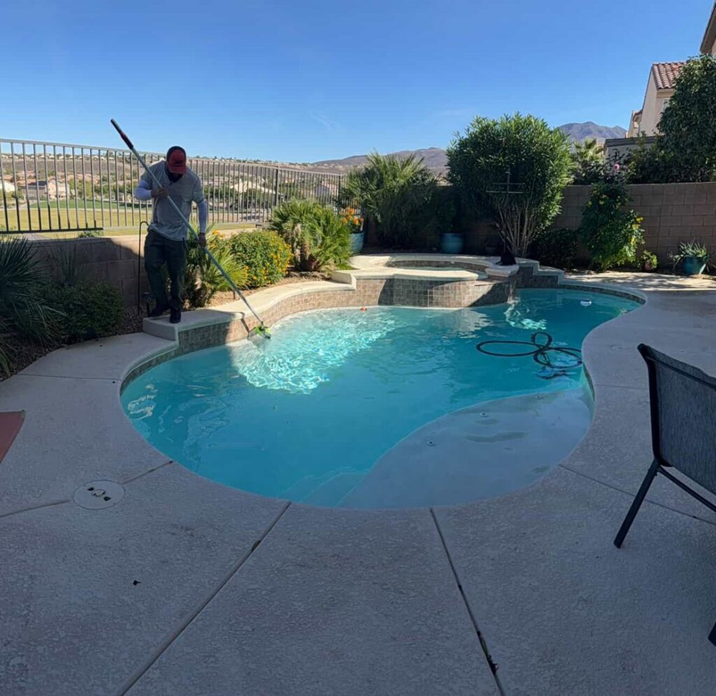 A person actively cleaning a swimming pool with a long pole for Suburban Pool Company in Germantown, WI.