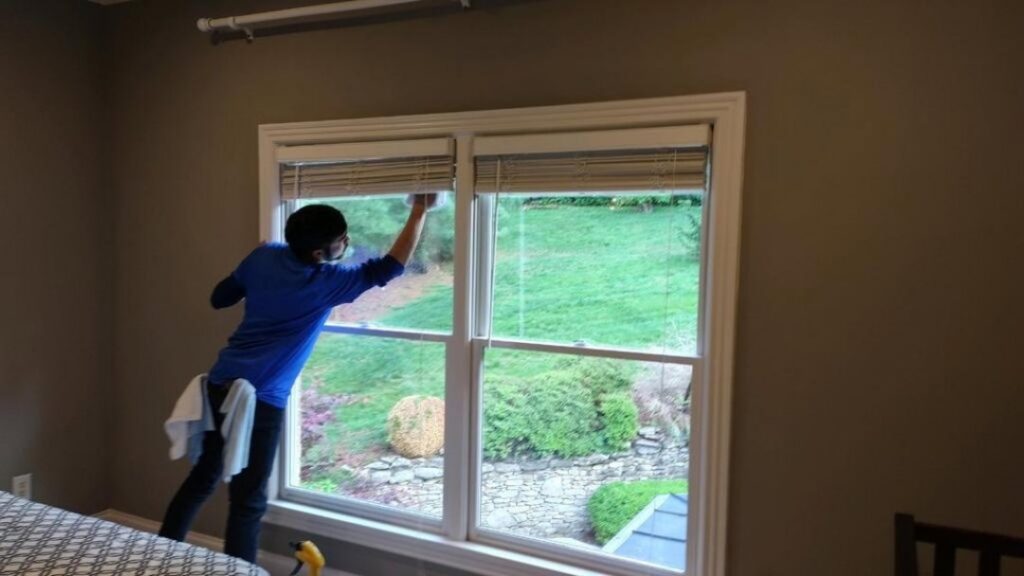 A professional cleaner from Absolute Luxury, LLC Residential & Commercial Cleaning meticulously cleans a window in a home in Antioch, TN.