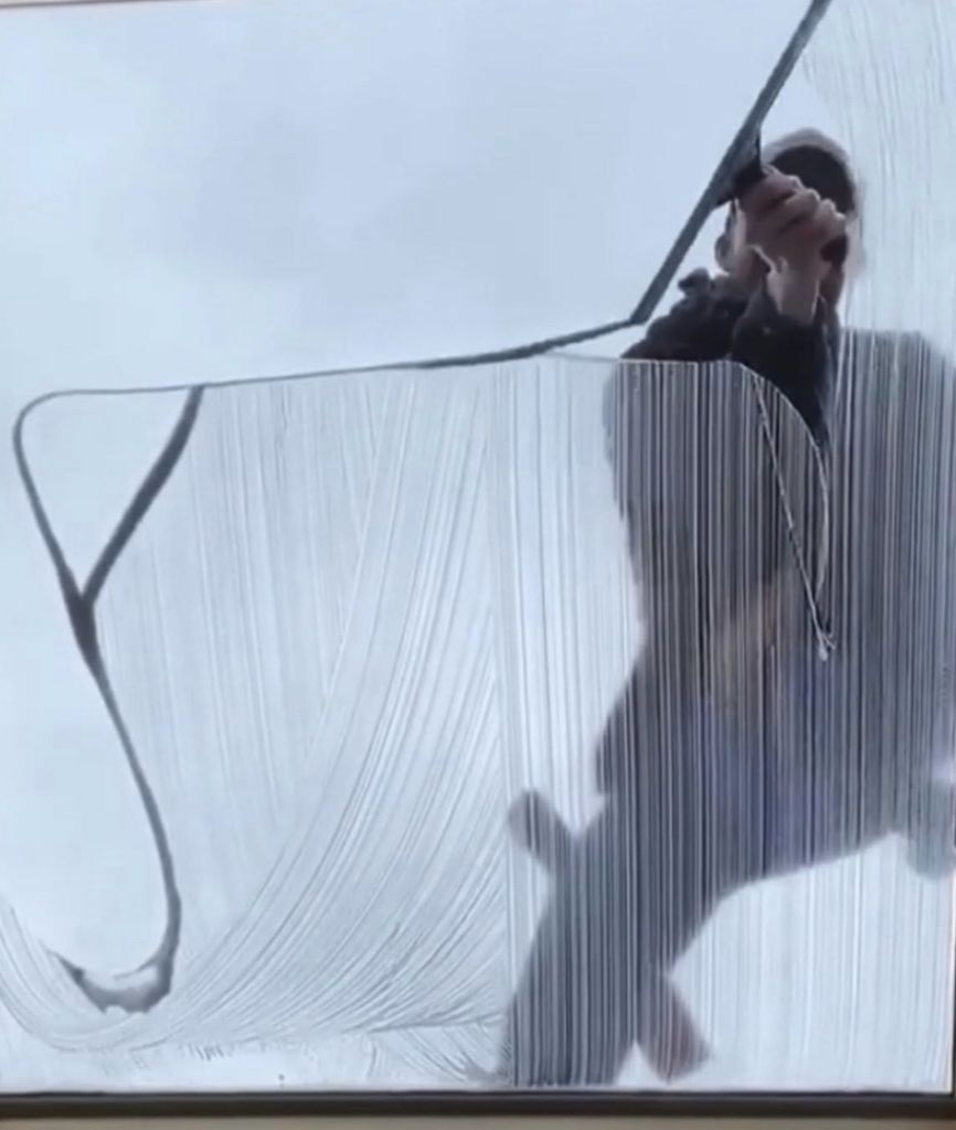 A person cleaning a window with a squeegee, demonstrating window cleaning services by Essential Cleaning in Henderson, NV.
