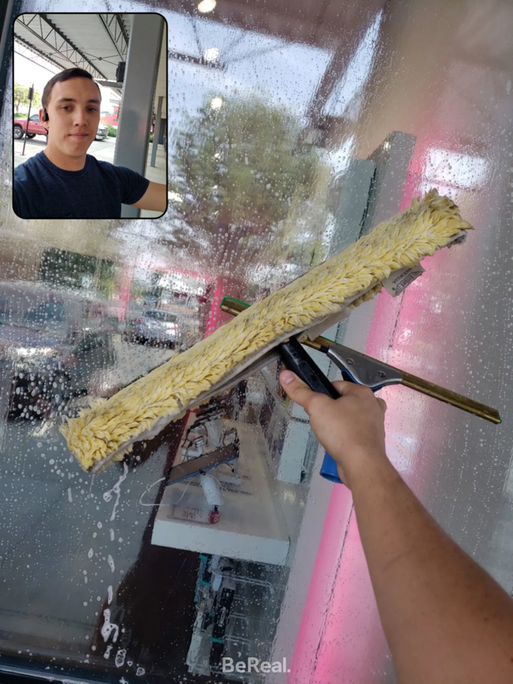 A person's hand using a squeegee to clean a window, demonstrating window cleaning services by Gavin's Cutting Edge in Moscow, ID.