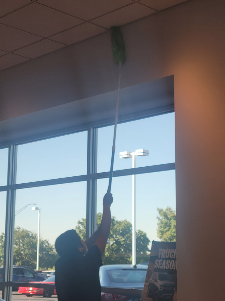 A cleaner from Arroyos Cleaning LLC dusting a high ceiling in Fort Myers, FL.